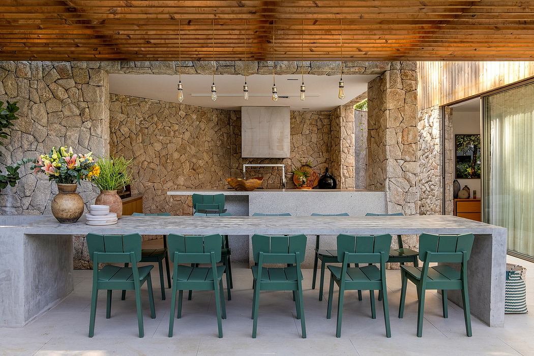 Rustic stone walls, modern concrete bar, and vibrant green chairs create an inviting outdoor dining space.