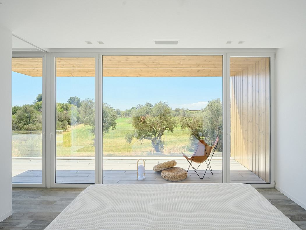 Spacious room with large windows overlooking a lush, natural landscape. Minimalist design with wooden accents.