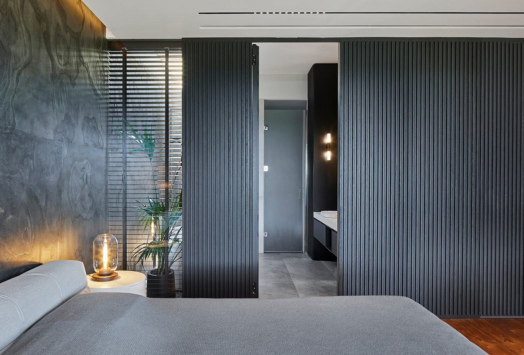 Minimalist bedroom design with dark wooden paneling, sliding doors, and warm lighting.