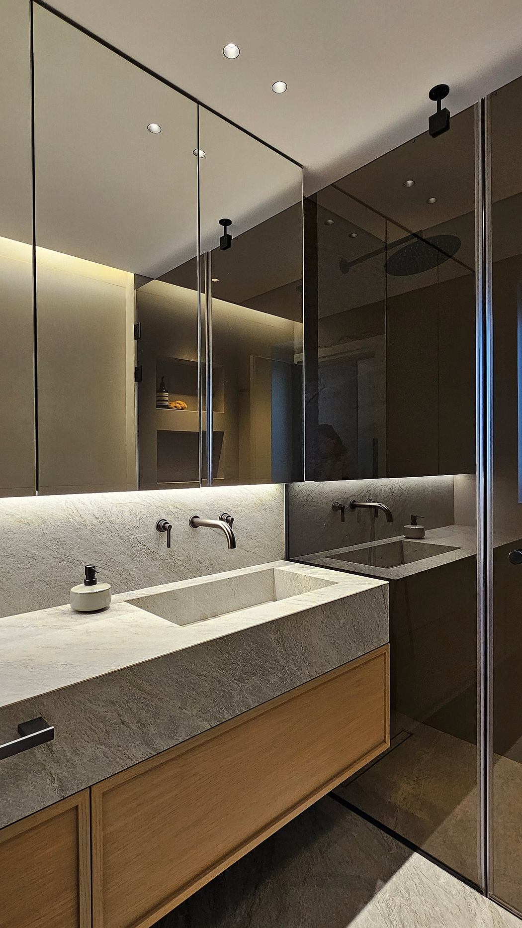 Sleek, modern bathroom with a large mirror, stone vanity, and recessed lighting.