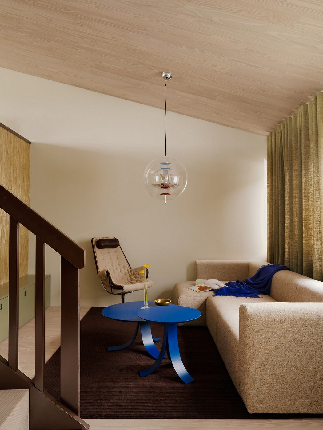 Cozy living room with wooden ceilings, plush couch, and modern blue accent table.
