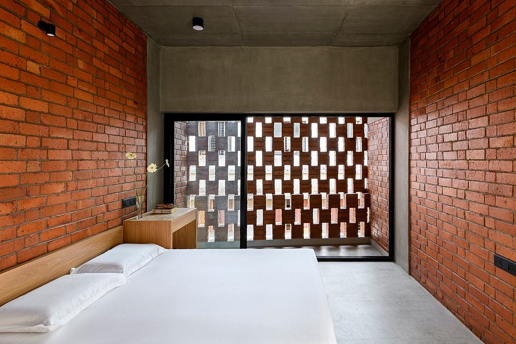 A modern minimalist bedroom with exposed brick walls, a glass partition, and a wooden nightstand.
