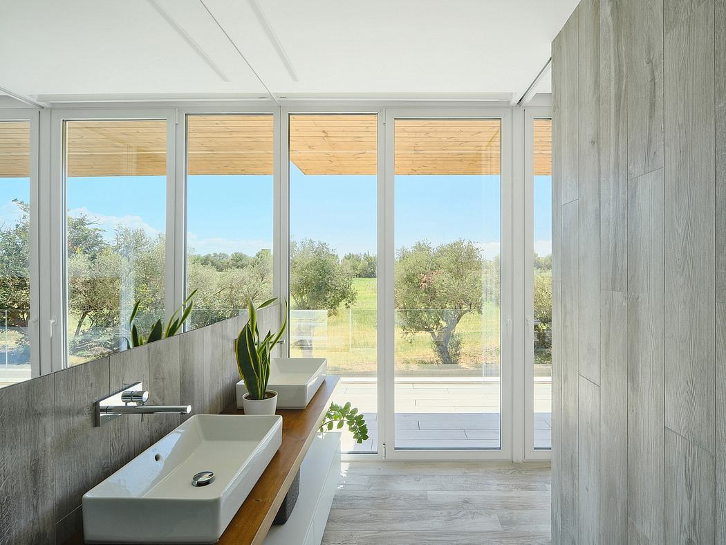 Modern bathroom with minimalist design, large windows overlooking lush outdoor scenery.