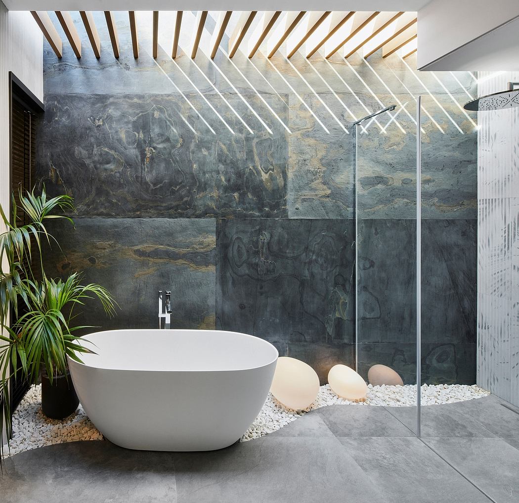 Spacious bathroom with modern bathtub, stone walls, and natural light-filled ceiling.