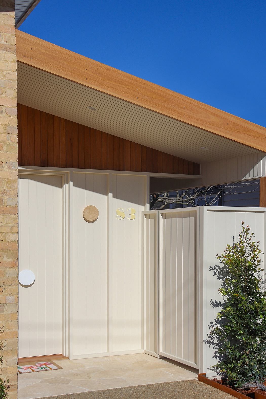 Wooden roof overhang, white textured walls, and a decorative doorway with geometric accents.