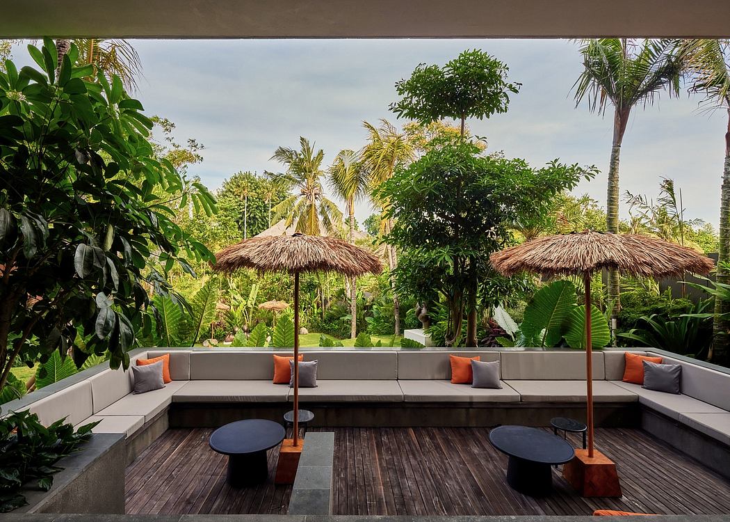 Lush tropical garden setting with modern wooden deck, plush seating, and thatched umbrellas.