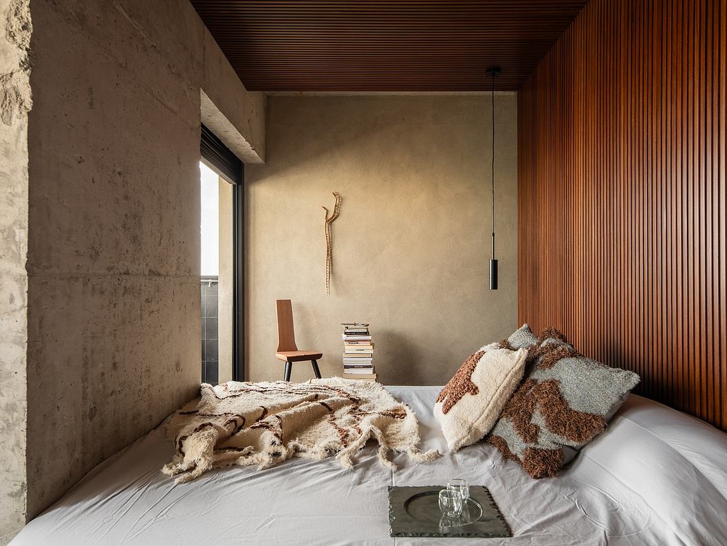 Minimalist bedroom with concrete walls, wooden ceiling, and cozy bedding arrangement.