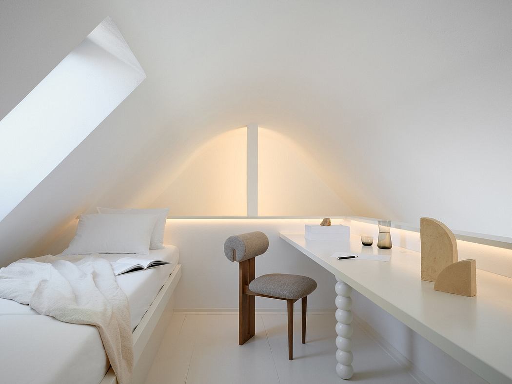 A cozy, minimalist attic room with a slanted ceiling, wooden desk, and gray chair.