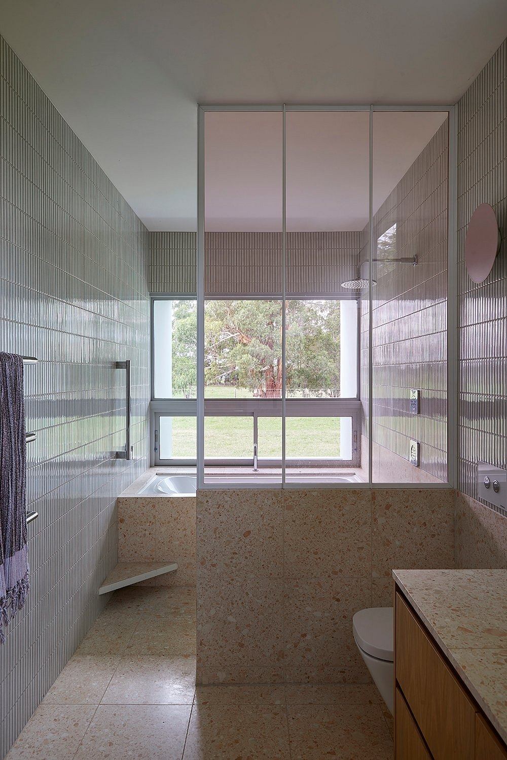 Spacious, modern bathroom with large windows, stone tile, and sleek fixtures.