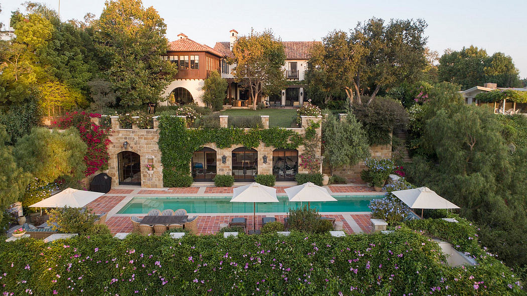 A sprawling Mediterranean-style villa with a lush garden, pool, and outdoor patio.