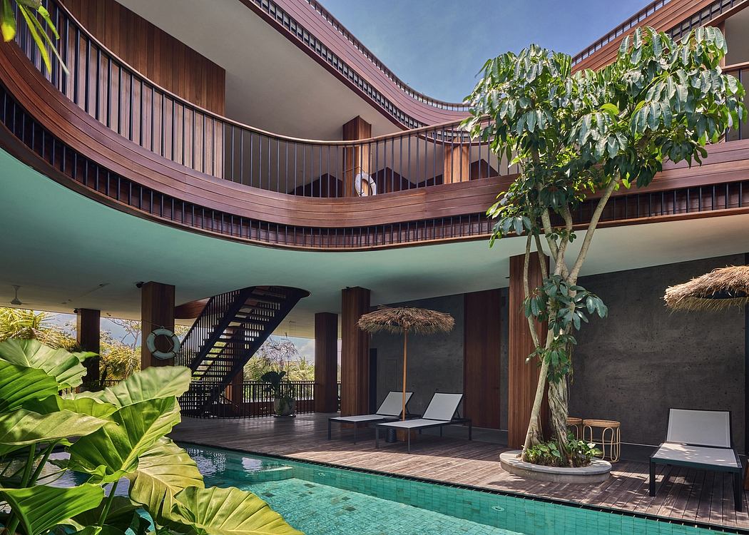 Curved wooden balconies, tropical foliage, and a pool in a contemporary hotel interior.