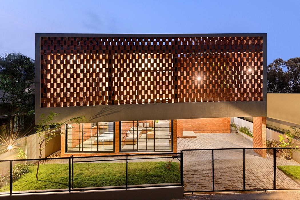 A modern building with an intricate wooden facade featuring a grid-like pattern, illuminated at night.