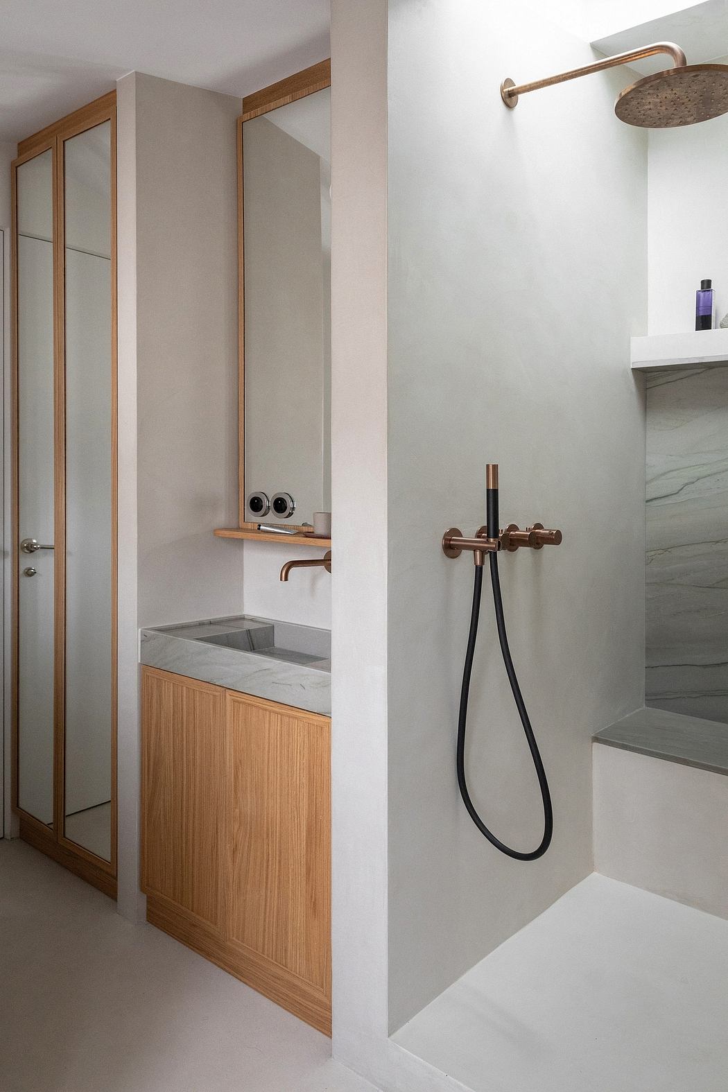 Minimalist bathroom design with wood vanity, brass fixtures, and glass shower enclosure.