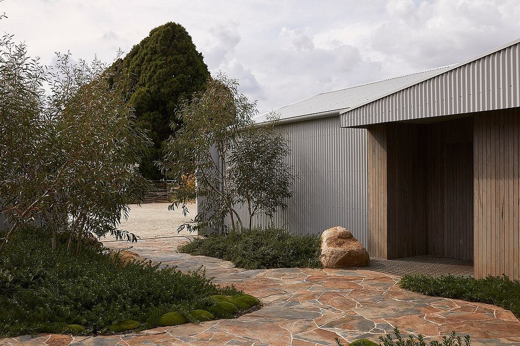 A modern, wooden structure nestled among lush, verdant foliage and a stone-paved path.