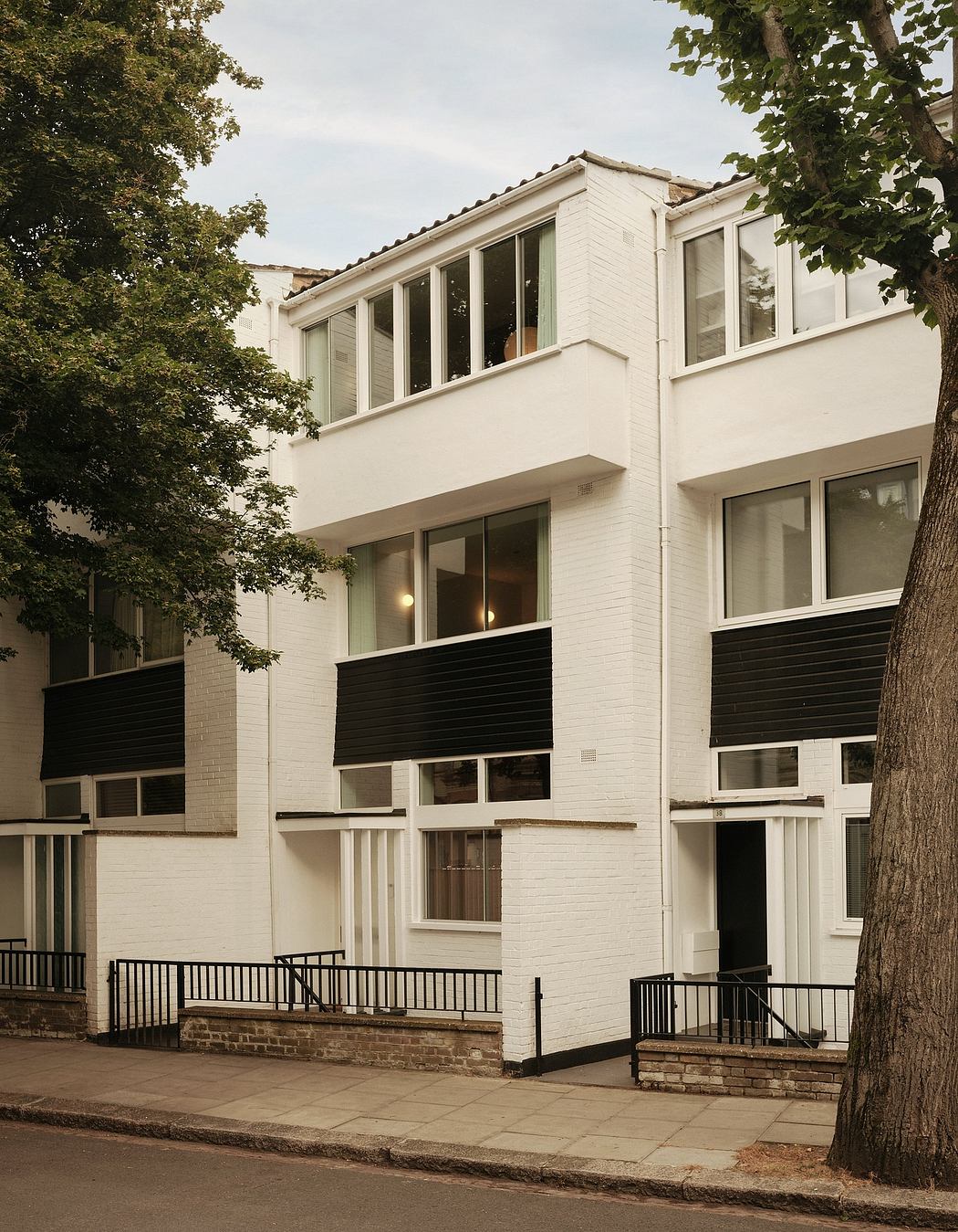 Modernist-style building with contrasting white facade, black balconies, and large windows.
