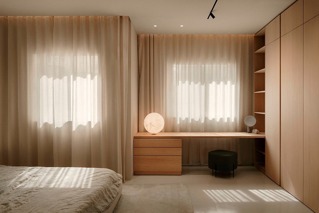A warm, minimalist bedroom featuring floor-to-ceiling curtains, wooden furniture, and recessed lighting.