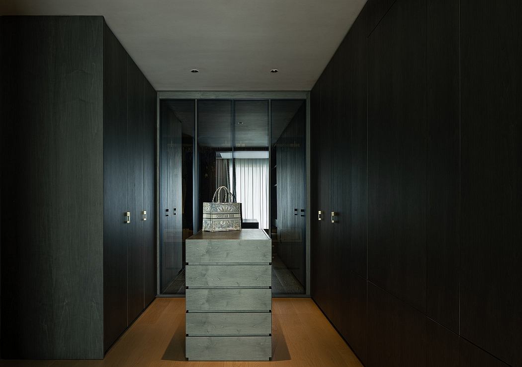 Sleek, minimalist interior with dark wooden built-in cabinets, drawers, and a light-colored floor.