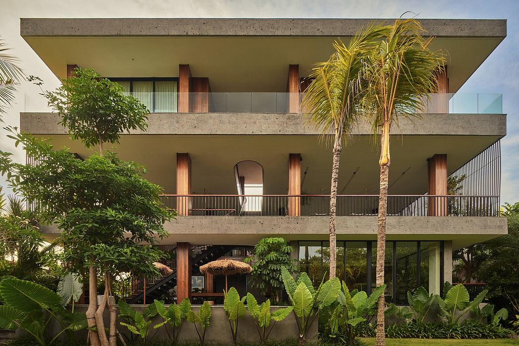 A modern tropical building with a lush, green balcony and palm trees.