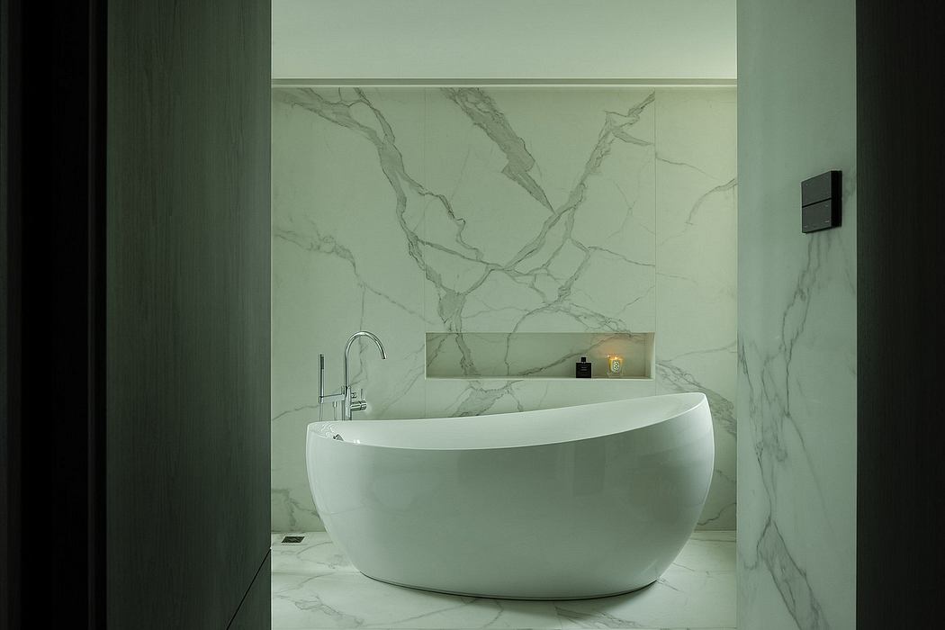 A modern bathroom with a freestanding, oval-shaped white bathtub and a marble-patterned wall.