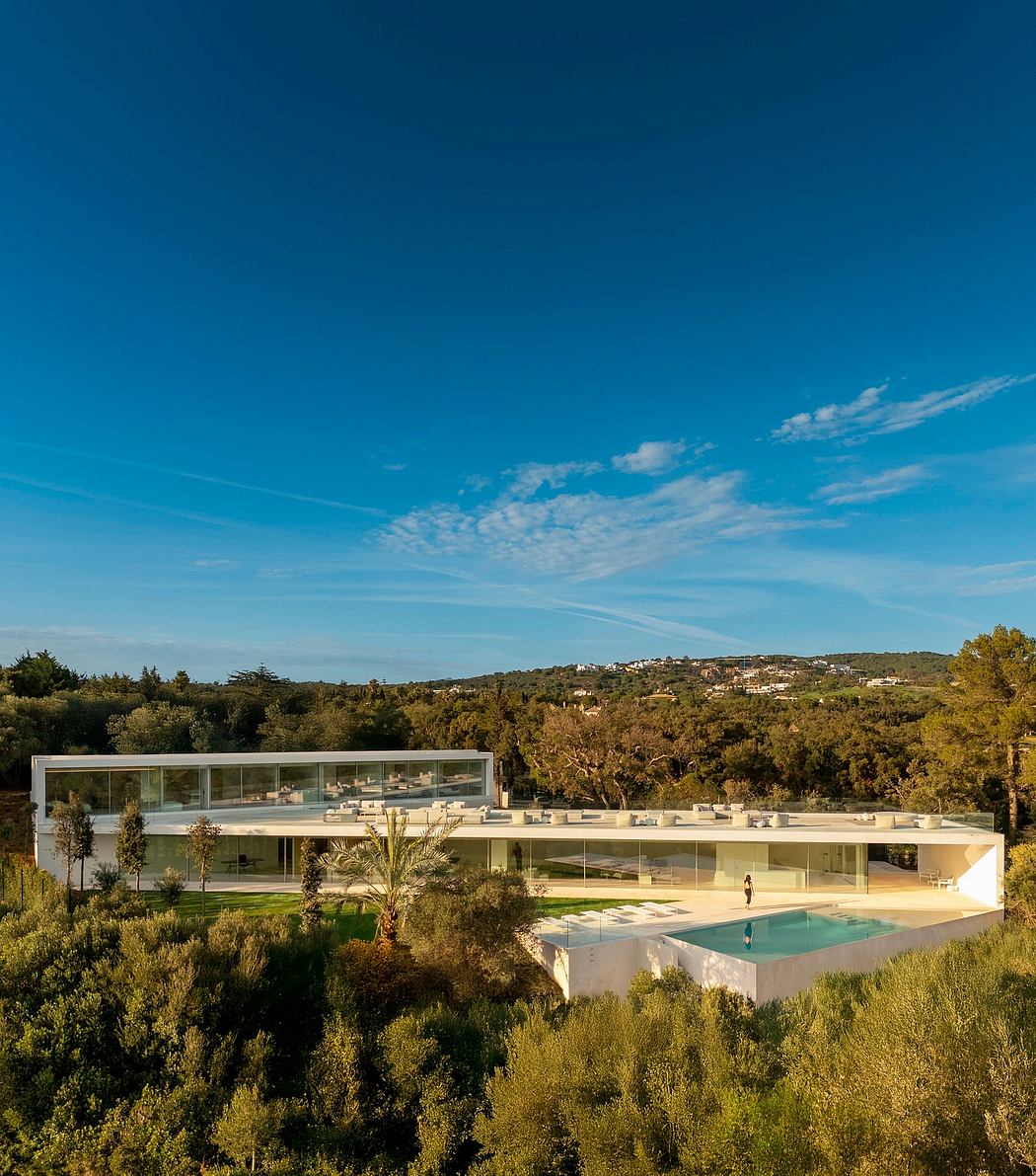 Stunning modern glass and concrete villa nestled in lush greenery, with pool and scenic backdrop.