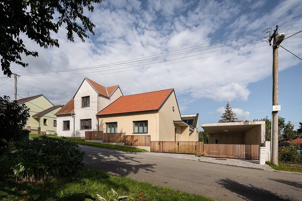 A residential building with architectural features including a pitched roof, wooden fencing, and power lines.
