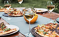 Dinner in a home garden. Pizza, salads, fruits and white wine on table in a backyard