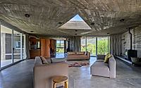 003-casa-cosmos-rammed-stone-and-exposed-concrete-on-a-sloped-site-edge.jpg