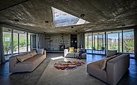004-casa-cosmos-rammed-stone-and-exposed-concrete-on-a-sloped-site-edge.jpg